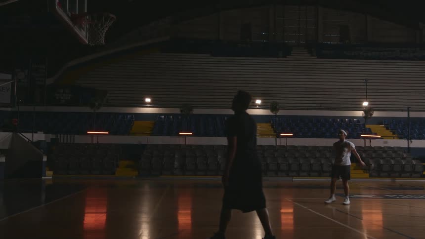 Coach teaching teenage girl how to throw a basketball