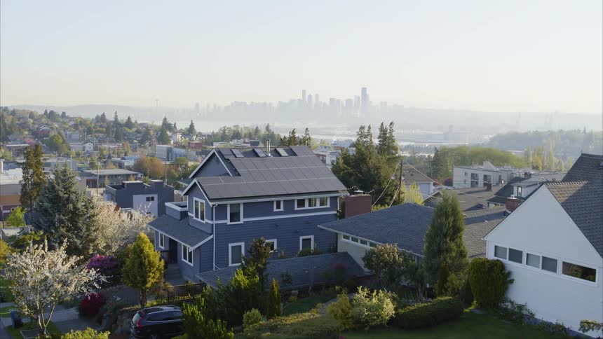 Slow push toward a beautiful home with solar panels covering the roof and a city skyline in the distance
