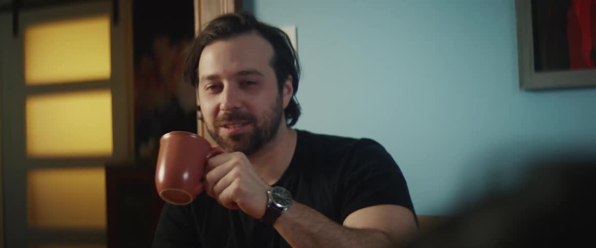 Man drinking a hot beverage and talking on the table at home