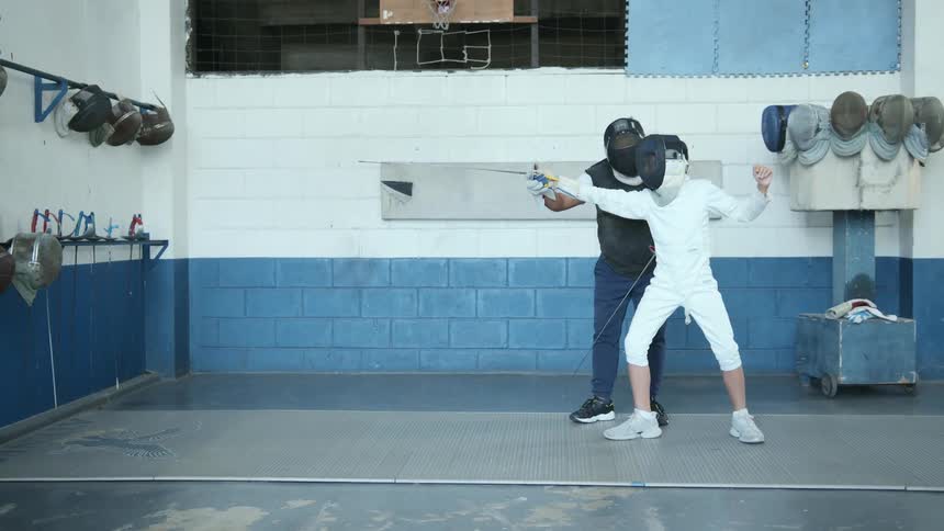 Coach training a studeng on fencing