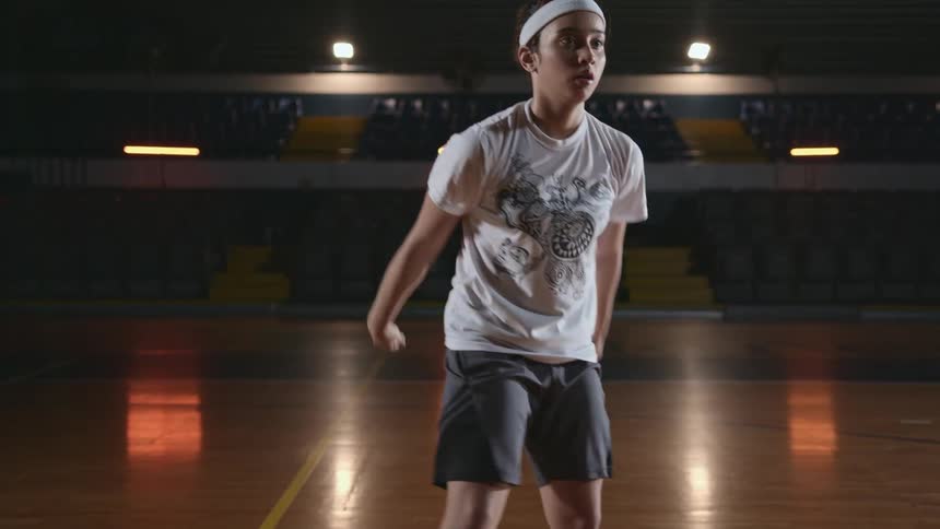 A teenage boy dribbles and throws a basketball