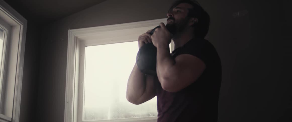 A man at home exercises with a kettle bell