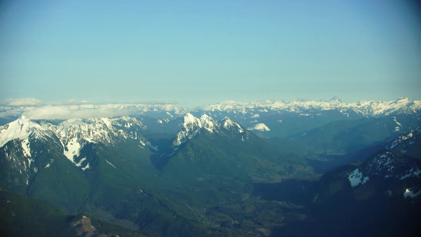 The high cascade mountains rise above North Cascade National Park in Washington State under a clear blue sky in winter