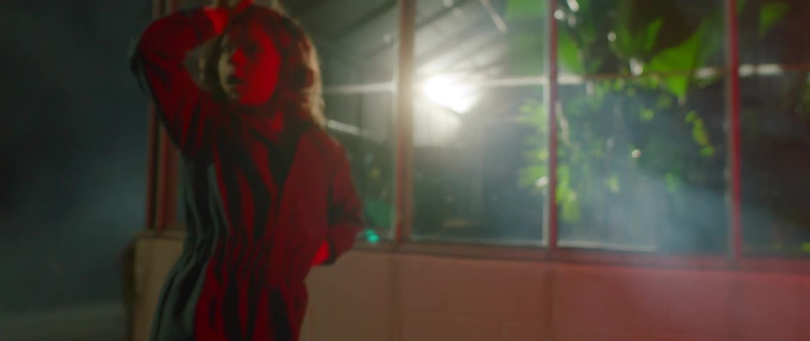 A young woman dancing in white fog outdoors at night time