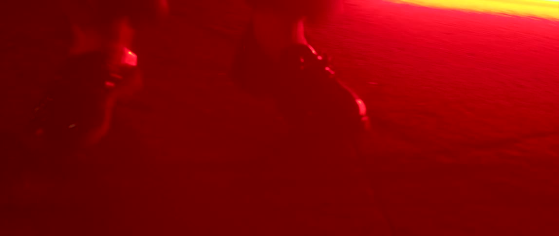A person dancing with a red light on the floor with a building in the background