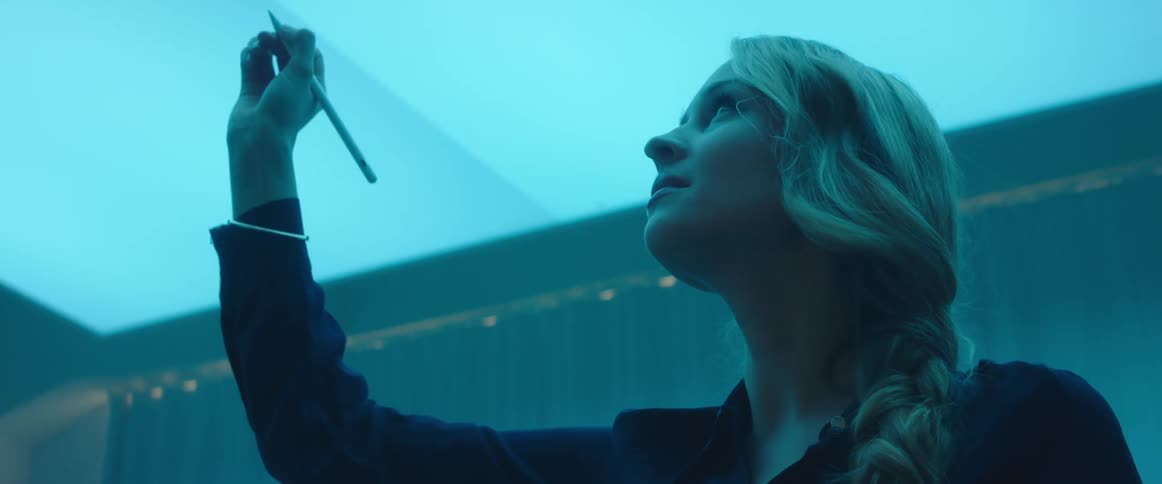 A woman drawing in the air standing in a room with a blue hue