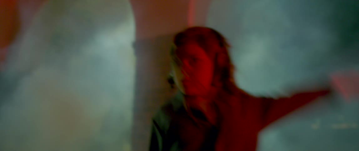 A woman dancing in fog outdoors at night time