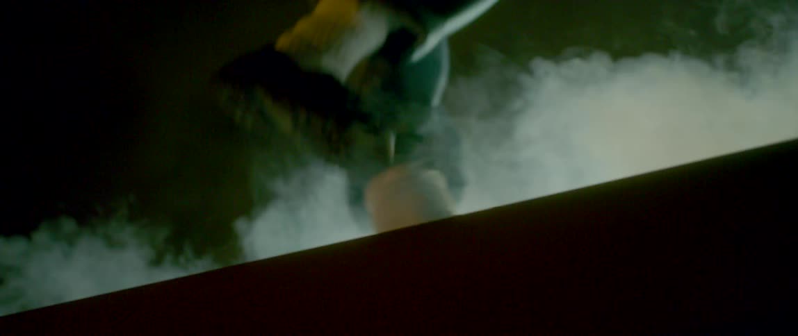 A person in black loafers stomps along the edge of a cliff as smoke rises