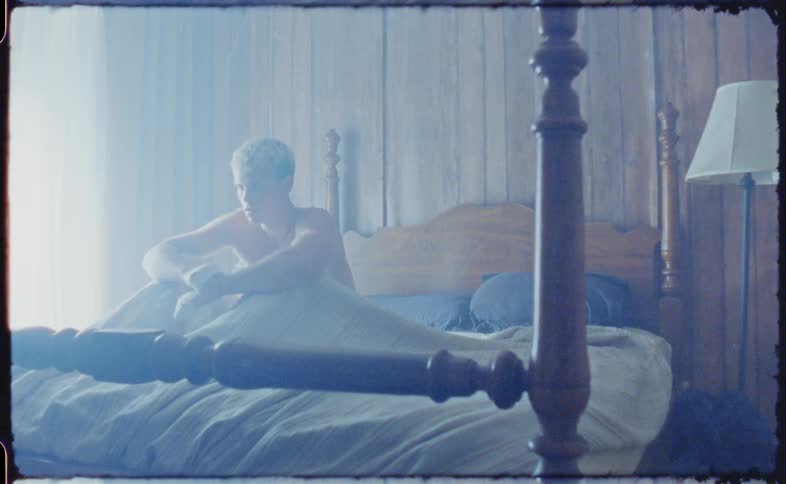 A shirtless man sitting up abruptly while sleeping in a bed
