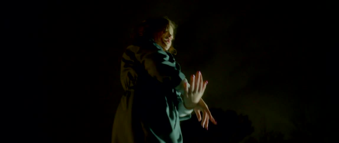 Girl wearing overalls dancing outside a building at night