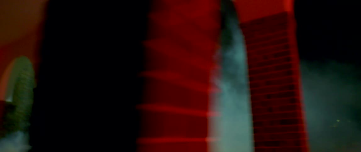 Girl wearing overalls running out a building at night through white smoke