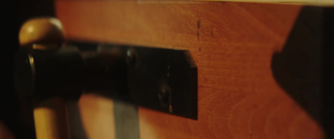 A hand turning a crank on a wooden vice