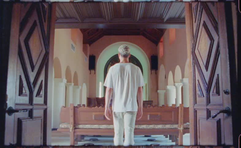 A man walking through a doorway with pillars and arches in the room