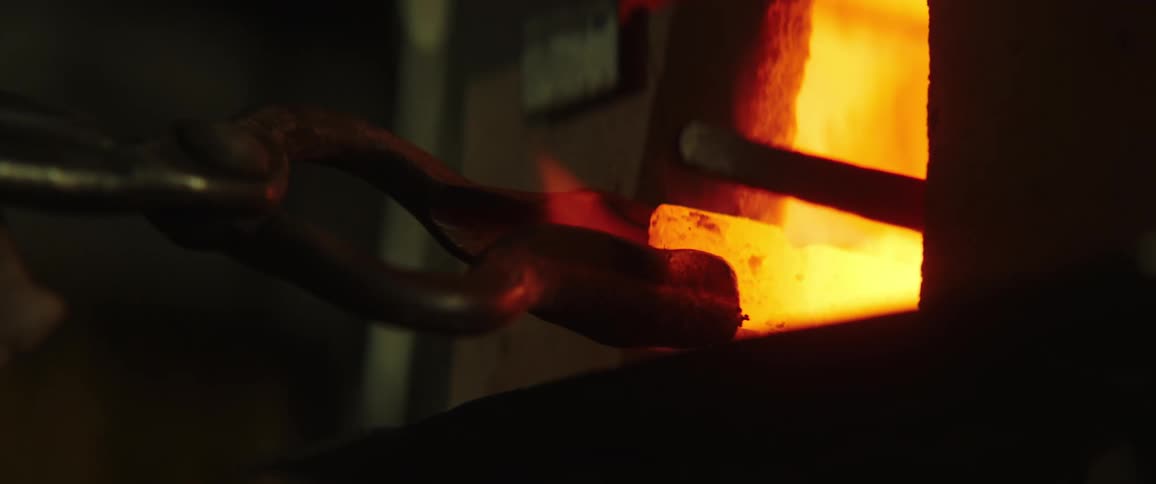 A person pulls a hot coal out of a flames with tongs
