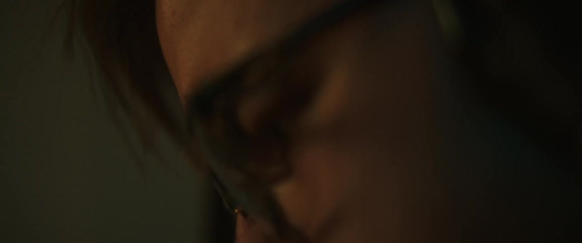 A man with glasses and headphones in a room with a wall in the background