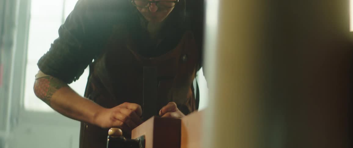 A man adjusting a piece of work on a table indoors