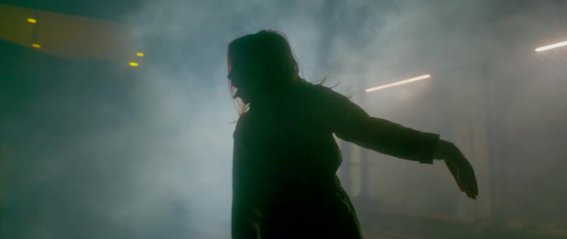 Woman with braids and headphones dances in the fog indoors