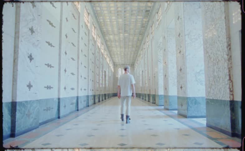 A man is walking through an empty building hallway