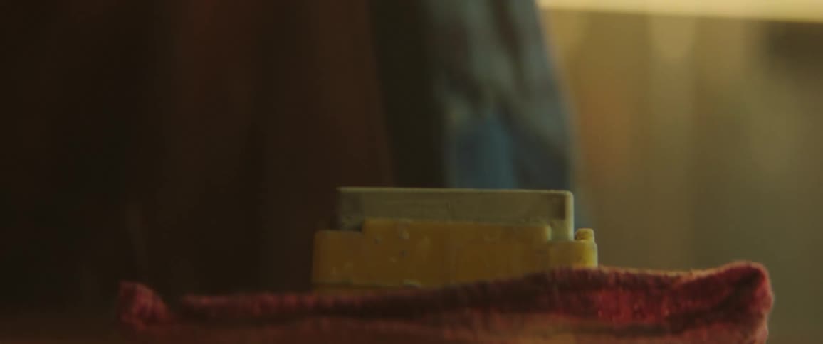 A man holds a knife while using his other hand to stack blocks that he sprays with water