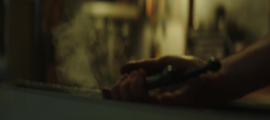Blacksmith quenching the blade of a knife in oil using tongs