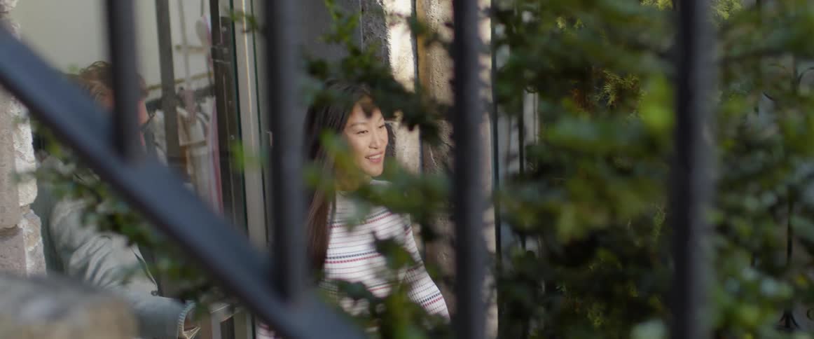 A woman smiles and looks back at a man who held the door open as they exited a building