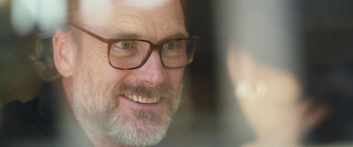A man with glasses talking to a woman