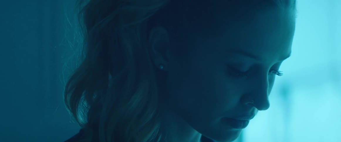 A woman is looking down in the dark room