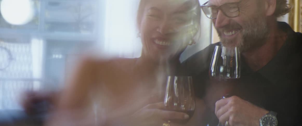 Happy couple smiling and laughing while drinking wine in a restaurant