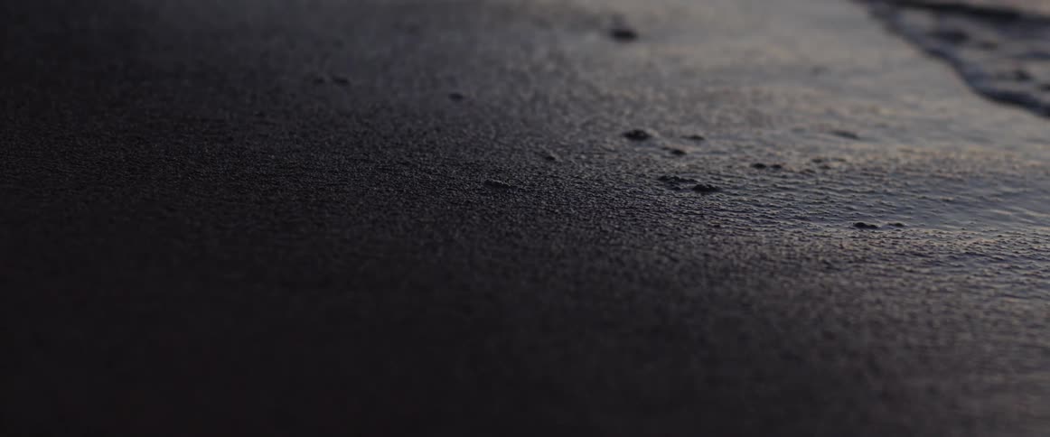 Small waves washing over the sand on the shoreline at evening