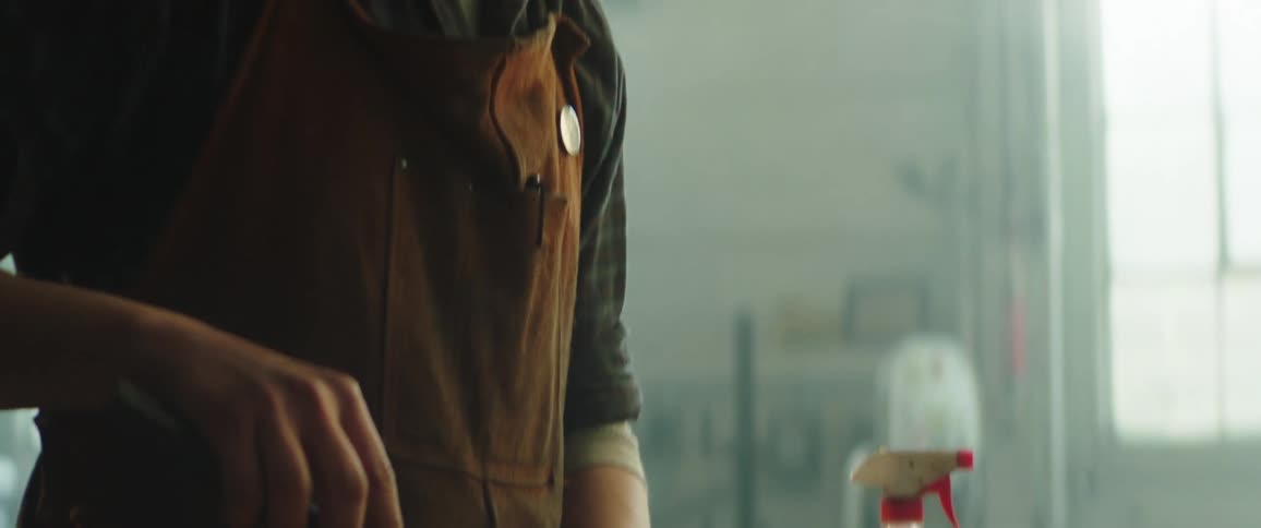 A man sharpens a long blade knife in his workshop