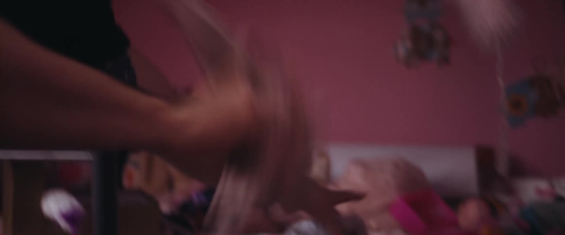A man in a bedroom putting clothing in a hamper with a wall and a bed in the background