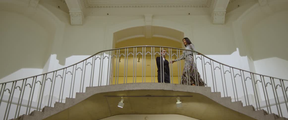 Couple walk up different staircases to greet each other near doorway