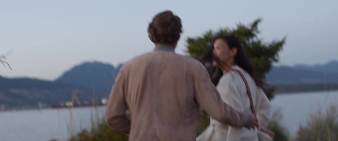 Couple on a date running on a dirt path near a lake at sunset