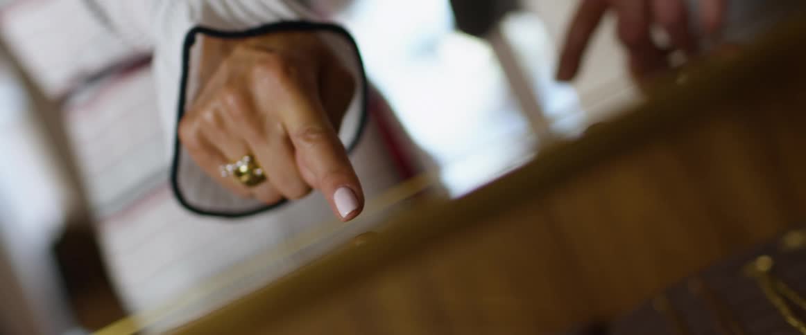 A person in a room rubbing their hands on a table with a wall and window in the background