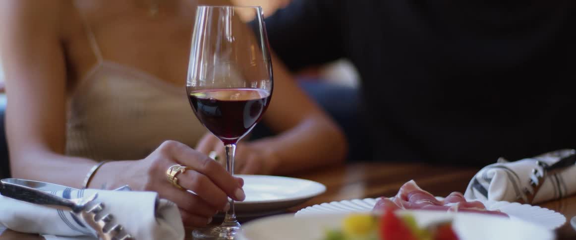 A man and a woman sitting at a table in a restaurant holding glasses of wine