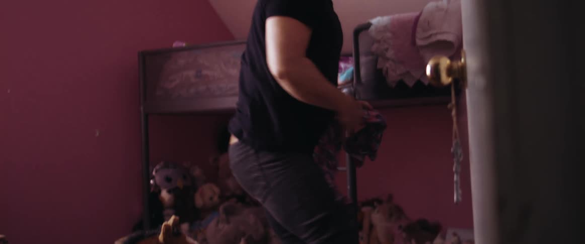 A man ina childs room folding clothing and hanging clothing