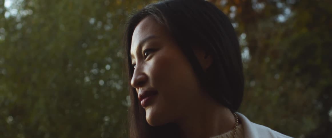 Woman talking and nodding while standing outdoors at sunset