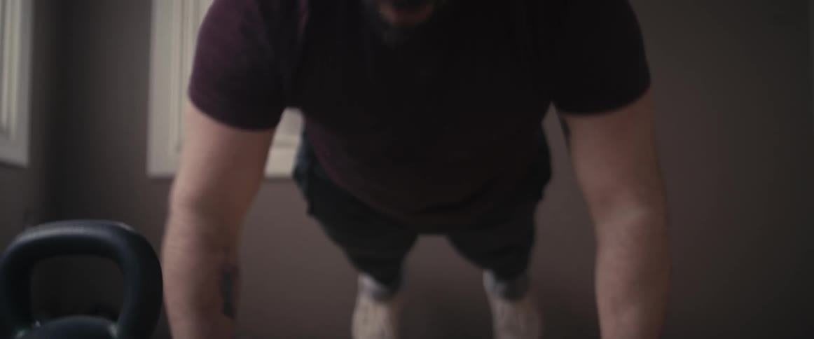 Man does push ups on floor near weight and window