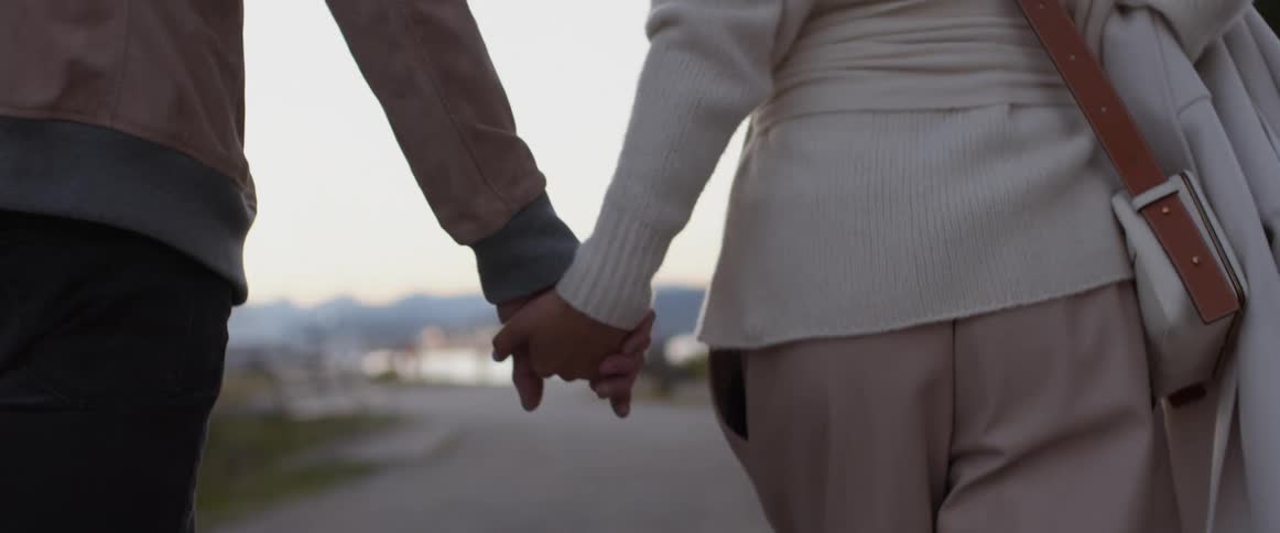 Man and woman holding hands walk down the road