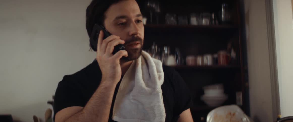 Bearded man answers a phone call in the kitchen at home