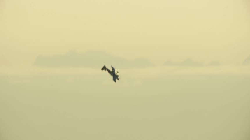 Single engine airplane climbing steeply before diving back down into the snow covered valley below in winter