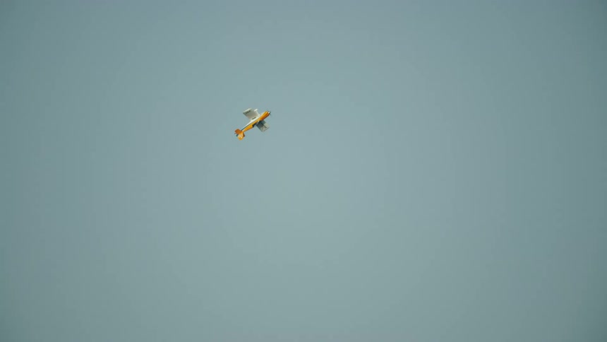 A single engine passenger airplane is looping before diving back into the clouds. inthe valley below
