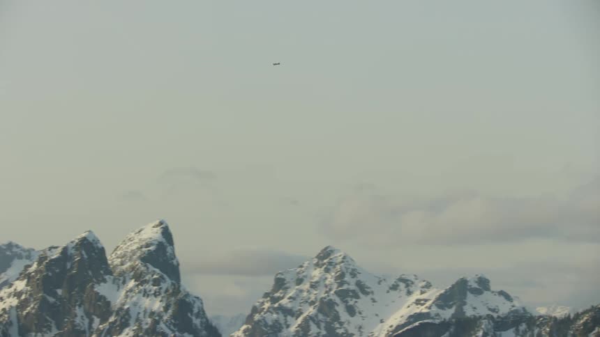 The small single engine airplane on the way back to the airfield flying high above tooth shaped mountain peaks covered in snow deep in the winter