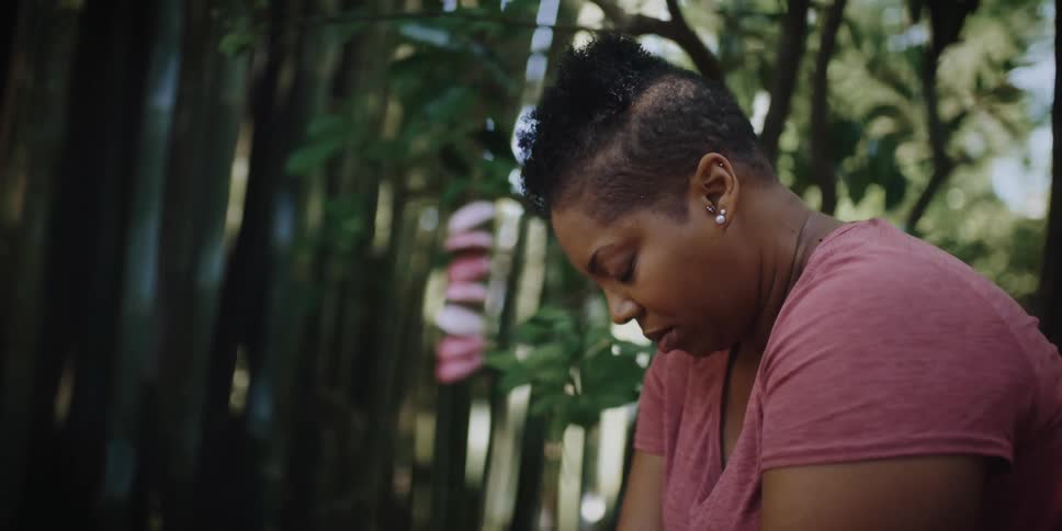 A woman sits with her head bowed as she meditates outdoors