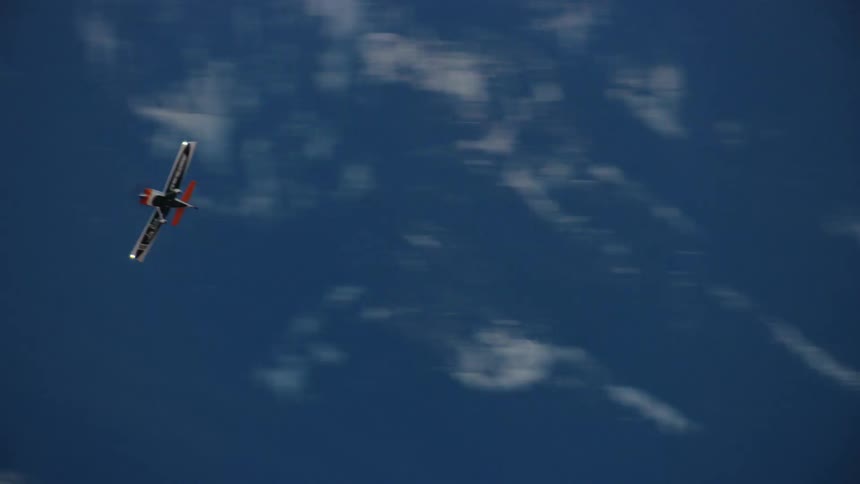 An orange Vans RV single engine acrobatic airplane flies maneuvers above the North Cascade Mountains in winter