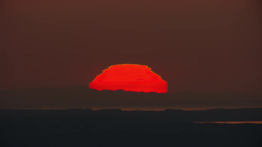 An intense and dramatic orange and red glowing sun drops below the horizon after an awesome day flying acrobatic airplanes
