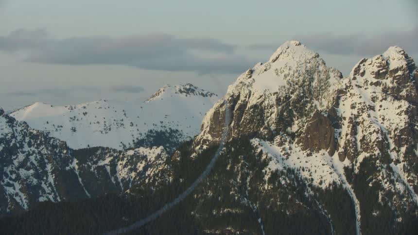 Single engine aircraft doing acrobatic maneuvers over the snow covered peaks of a mountain range in the heart of winter