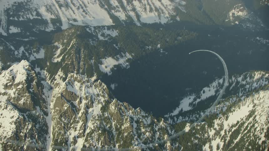 An acrobatic airplane performs loops near jagged and dramatic snow covered mountains in the North Cascades outside of Seattle, Washington