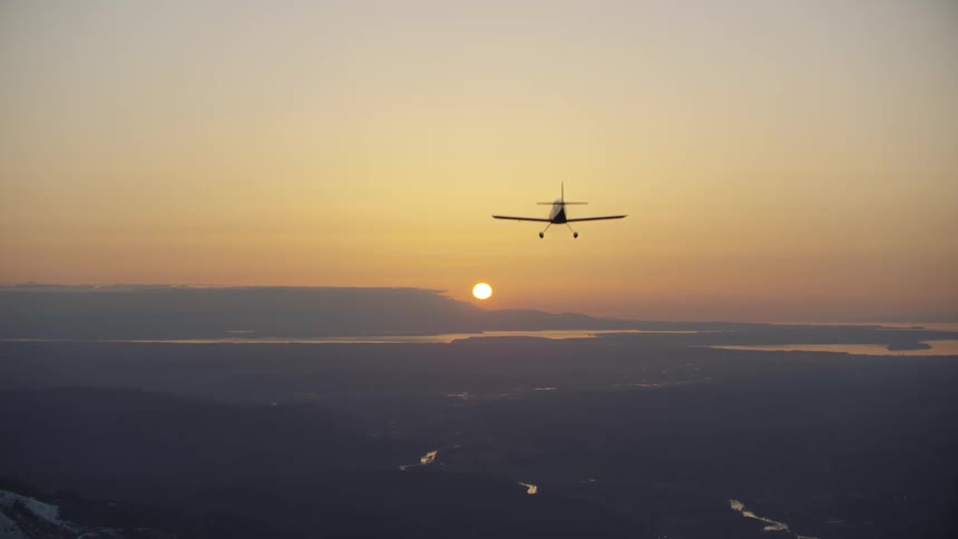 A small single engine aircraft flies directly overhead towards the setting sun after a great day of air travel