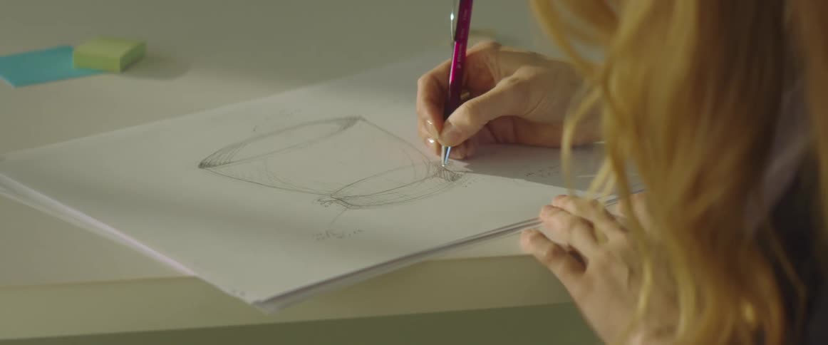 Woman drawing a cup using a mechanical pencil on paper